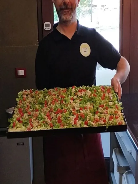 Denis mostra una teglia di pizza fredda con insalata, pomodorini e gamberetti