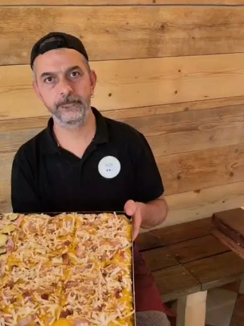 Denis Vecchi nel locale, con in mano una teglia di pizza alla zucca