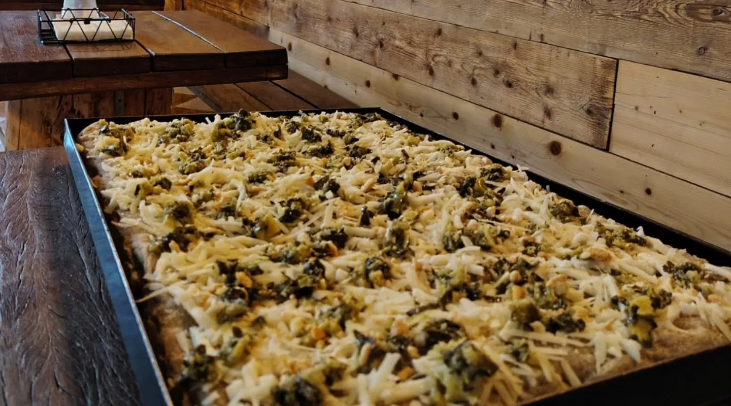 Una teglia con Monte Veronese e broccoli di Novaglie sul tavolo di legno di Pizza Voglia