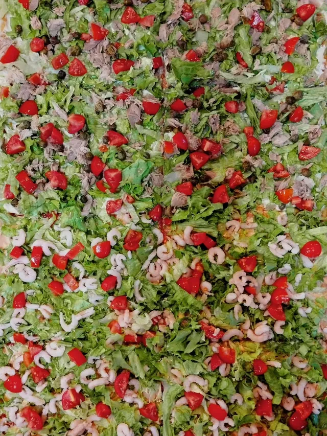Pizza fredda in teglia con insalata, pomodorini e gamberetti, vista dall’alto