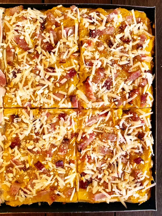 Teglia di pizza alla zucca già divisa in tranci, vista dall’alto